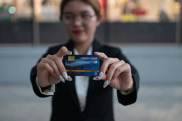 Young woman holding credit card, smiling confidently, representing modern banking, online shopping, wealth and smooth e-commerce transactions.