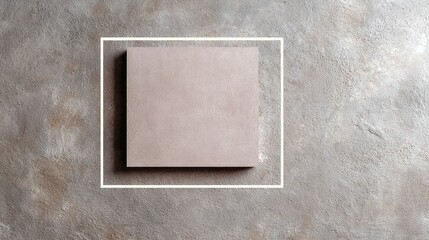 Square object on a textured gray surface with a white border around it.