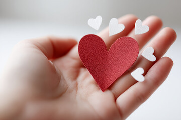 Obraz premium Red heart held in hand, surrounded by small white hearts, symbolizing love, care, Valentine's Day, and affection