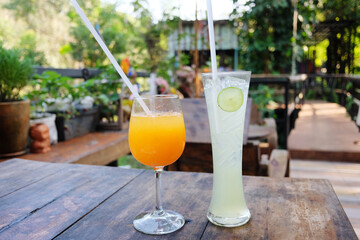Freshly glass of ice orange juice and lemon juice on wooden table