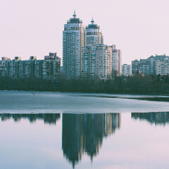 Fototapeta premium Square Stock Photo of City Buildings Near River Shore Reflects in Calm Water