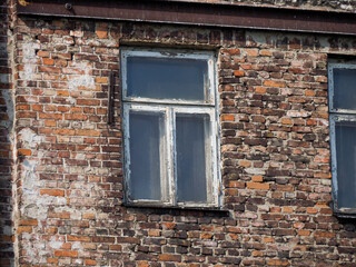 Old weathered brick building facade with single window and deteriorating wall texture