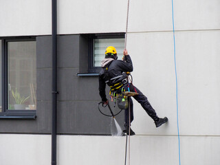 Professional Window Cleaner in Safety Equipment Working on Modern Office Building Exterior