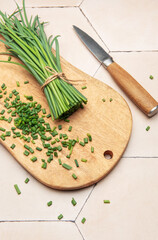Freshly cut chives on wooden cutting board with knife