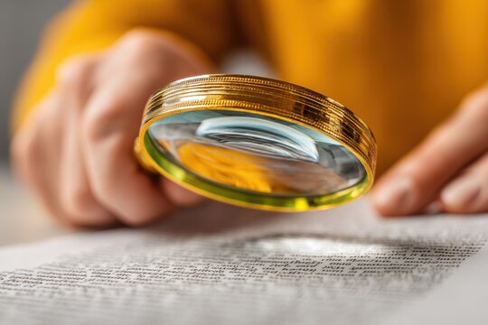 Document review with magnifying glass, focusing on textual analysis for research, verification, and detailed inspection of writing.