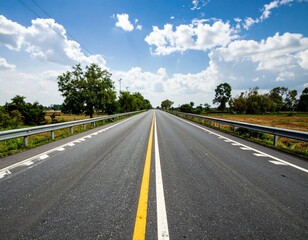 Fototapeta premium Expansive Open Road Under Bright Blue Sky and Fluffy White Clouds