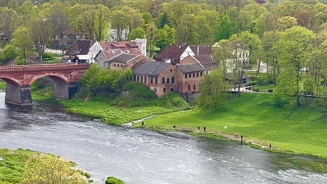 Fishermen line the grassy bank of the Venta River in spring during vimba migration in Kuldīga
