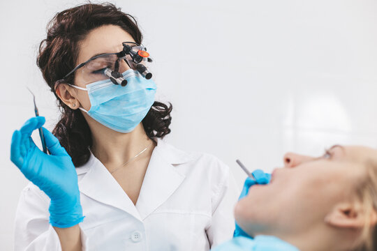 Female dentist examining patient's mouth using stomatological binoculars. Using modern technologies in medicine.