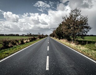 Fototapeta premium Serene Empty Road Leading Through Fields Under Dramatic Sky
