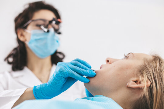 Female dentist examining patient's mouth using stomatological binoculars. Using modern technologies in medicine.