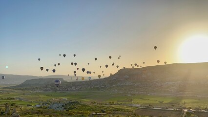 Colorful hot air balloons rise gracefully in the sky over Goreme, Cappadocia at sunrise, offering a breathtaking view of the unique rock formations and valleys below