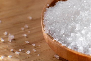 Crystal clear white sugar crystals macro close-up, spoon and wooden cutlery