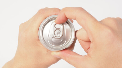A close up of two hands opening a silver aluminum can.viewed from the top.
