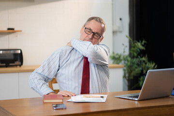 Male businessman is doing a stretchy posture due to sitting in the kitchen for too long.