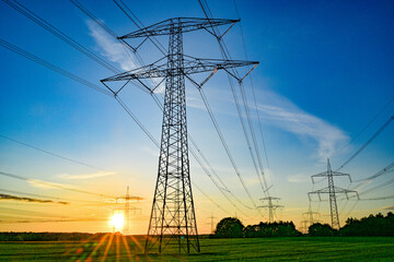 Power poles in spring, sunset, in the field and on the meadow, Brandenburg, Germany