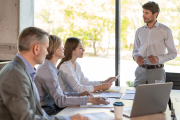 Successful businesspeople working in a coworking space working with laptop discussing strategy and business plan in modern office.
