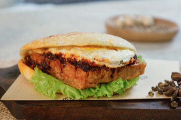 Sandwich with fried egg and vegetables on a wooden cutting board