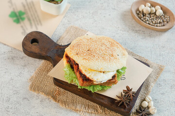Homemade hamburger with black sesame bun on wooden cutting board