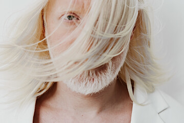Portrait of a man with long, flowing white hair against a soft, neutral background, exuding a...