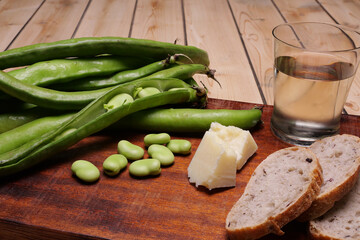 Fave con formaggio, pane e bicchiere di vino bianco sul tagliere