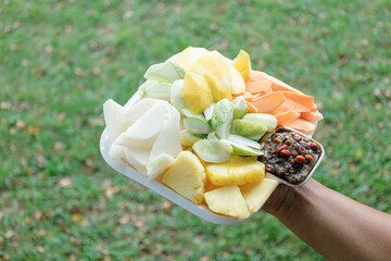 Fruit salad in plastic tray on green grass background