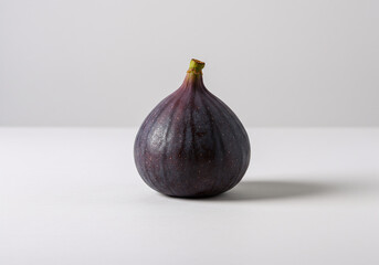 A Single Dark Purple Fig on White Background