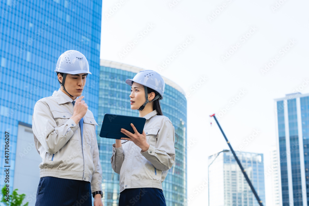 Aufkleber 建設現場でタブレットを見ながら打ち合わせする男女エンジニアのグループ