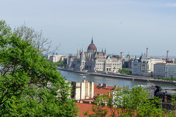 Panoramic view of Budapest city with Parliament building, Danube River, bridges and green trees under clear blue sky