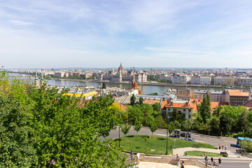 Panoramic view of Budapest city with Parliament building, Danube River, bridges and green trees under clear blue sky