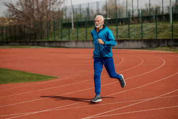 Full length of senior man running on stadium.