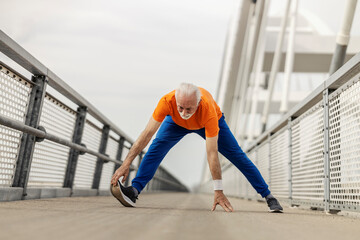 Full length of senior sportsman warming up on a bridge.