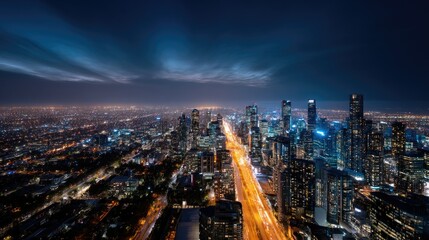 Fototapeta premium Panoramic view of a vibrant city at night from above, with streets lined with shimmering lights and skyscrapers glowing under the night sky