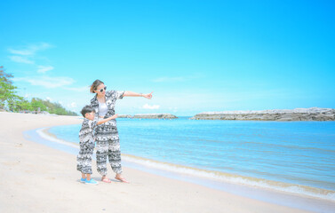 Seaside Serenity: A mother and child, dressed in matching attire, experience the magic of the shore together, against a vast clear sky.