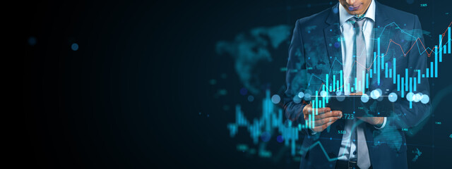 Businessman analyzing financial data on tablet with futuristic interface and glowing charts in dark digital background for market strategy concept.
