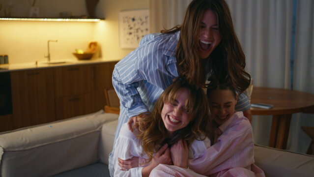 Emotional girls friends laughing together at home couch closeup. Overjoyed women