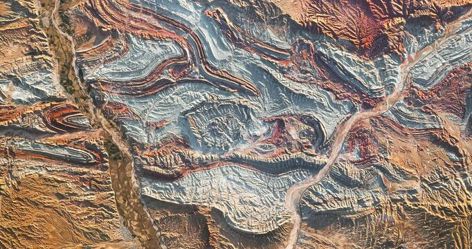 Aerial perspective on folded rocks with visible colorful layers . Camera is moving right and down. Animation based on image by NASA