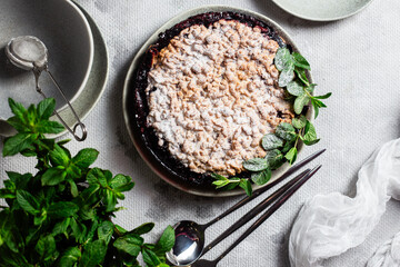 Round Pie with black currants and mint in a plate on the table. Dessert