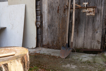 Old, rusty shovel and pitchfork leaning against a weathered wooden barn door. Rustic country scene...