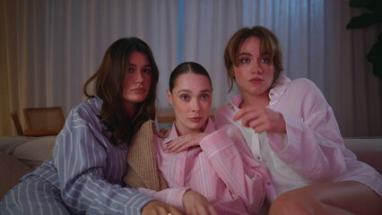 Girls shudder watching scary movie with popcorn at home couch night closeup. 