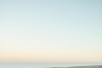 Obraz premium Serene dawn or dusk sky gradient with light blue and pale yellow hues, peaceful landscape with mist or water. 