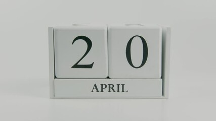 A hand flips a wooden calendar from April 20th to April 21st on a white background, signifying a shift in time, and reinforcing the idea of managing and organizing schedules effectively