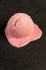 melting ice cream on a dark slate, sweet cold pink ice cream , closeup