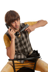 Holding a phone and gun while seated in a simple chair