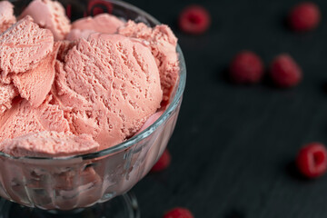 raspberry ice cream in a glass, sweet frozen red ice cream with raspberry flavor, The berries are scattered on the table