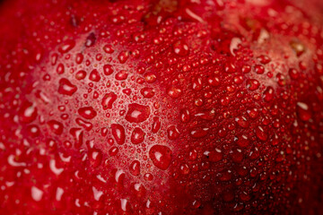 a wet red ripe pomegranate on a black table