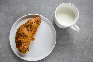 pistachio croissant and milk on gray surface