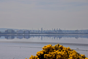 Chemical and industrial works on the south side of the Forth Estuary viewed across the Forth at low tide, Scotland, UK.