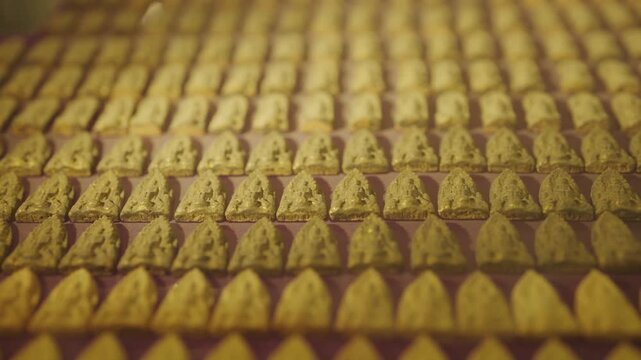 Rows of small traditional Thai Buddhist amulets neatly arranged on a display setup at an exhibition or a local amulet market in Thailand.