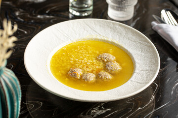 Portion of appetizing meatballs soup with star macaroni