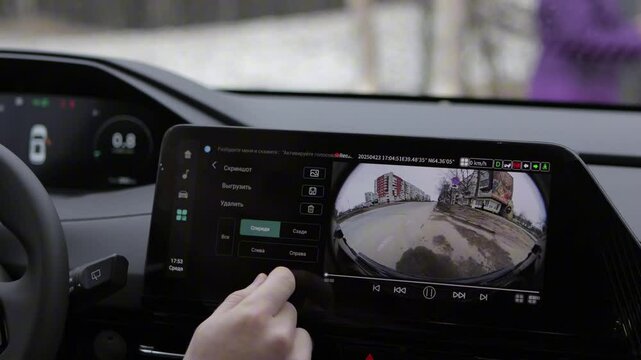 An individual is utilizing a tablet device specifically to observe the feed from a rear view camera that is installed in a cars interior